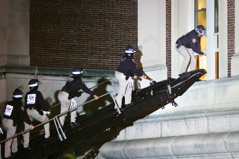 ضباط شرطة نيويورك يرتدون معدات مكافحة الشغب يقتحمون مبنى في جامعة كولومبيا.